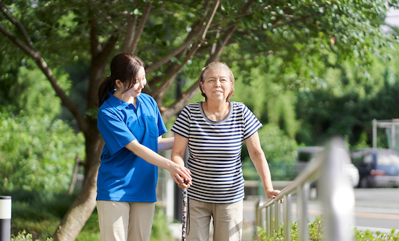 Elderly people walking with the help of a female caregiver